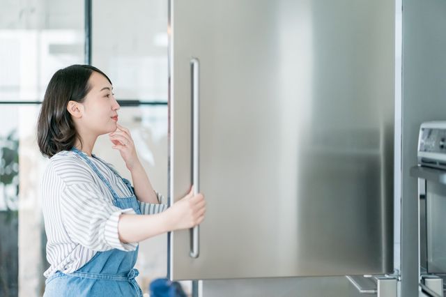 冷蔵庫を開けて考える女性