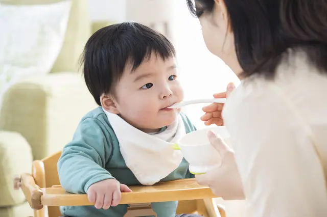 赤ちゃんに離乳食をあげるお母さん