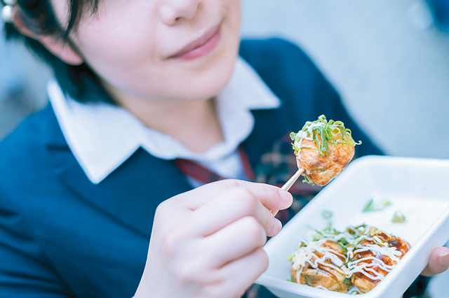 撮影のため手にしたたこ焼きをうれしそうにほおばる森松さん