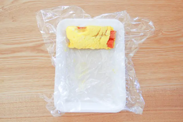 ラップをうまく使って卵を巻いていく|【コンビニ飯レシピ】10分でできちゃう!ラク早お弁当のおかずレシピ2選