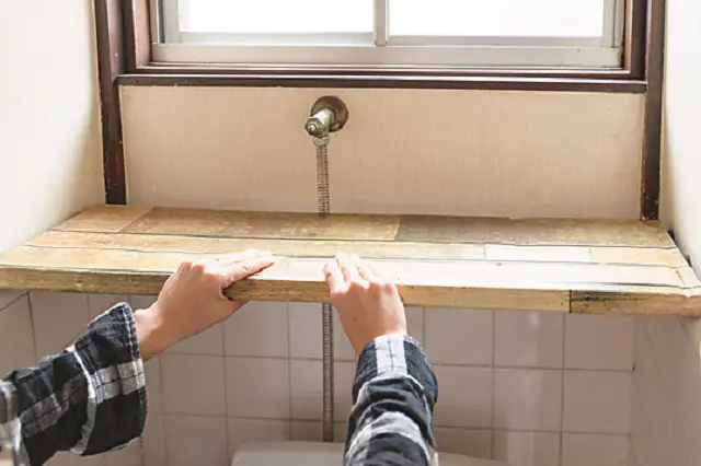 段ボールでつっぱり棒を挟むイメージ|【賃貸DIY】100均のリメイクシートと段ボールを使ってトイレに収納棚を作ろう!