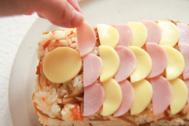 ハムとチーズを交互に並べてうろこを作ろう。丸のままのチーズは目玉になる|コンビニで買える食材で作れる!こどもの日のメニューにおすすめのレシピ!簡単&かわいい鯉のぼりの押し寿司でお祝いしよう