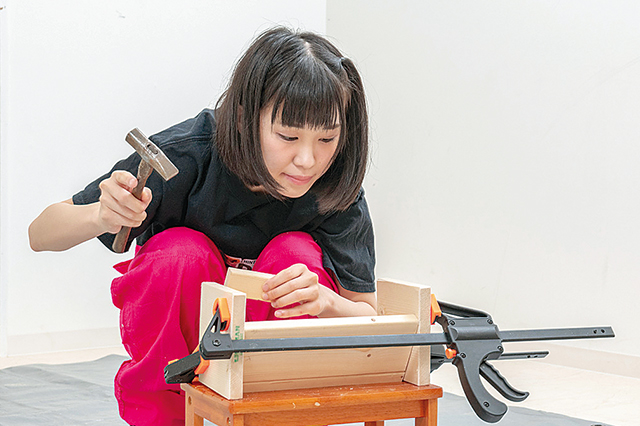 仮面女子・陽向こはるが挑戦するDIY作品「ミニブックスタンド」の作り方:バークランプで棚受けと側板を仮留めした状態で、棚受けの角度をとんかちで叩いて微調整