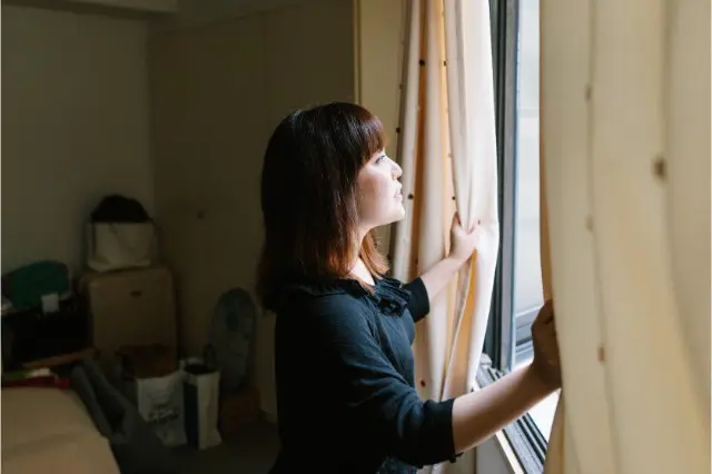 カーテンを開ける女性