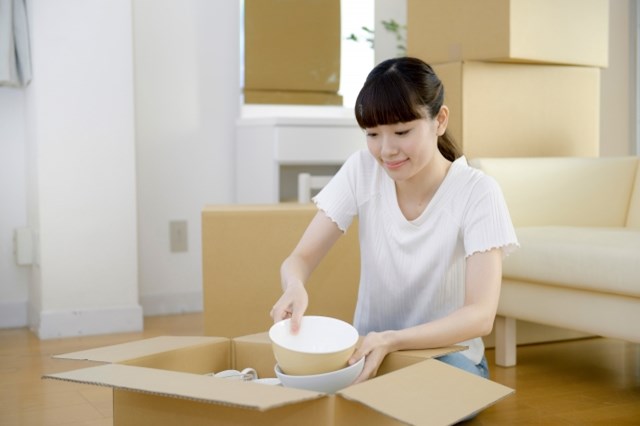 ダンボールから必要なものを取り出す女性