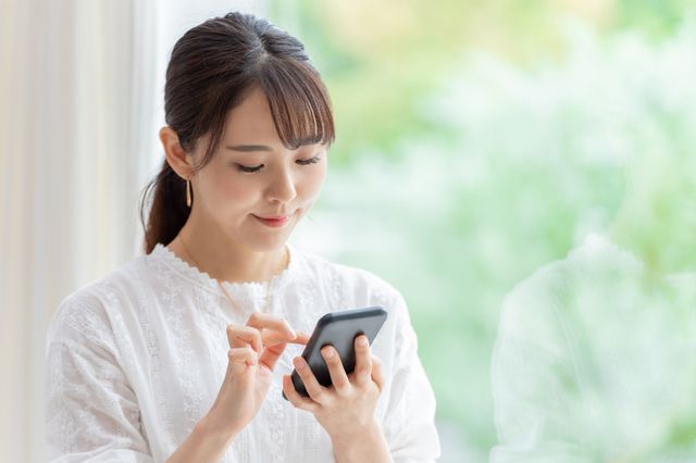 スマホを笑顔でいじる女性