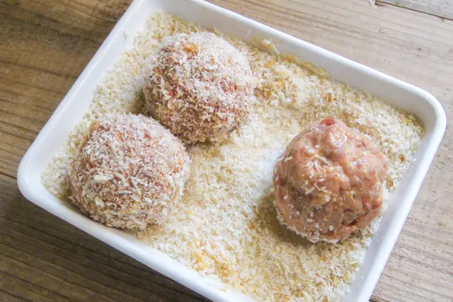 肉ダネを5~6等分にし、水をつけた手で丸くまとめ、小麦粉、とき卵、パン粉の順にまぶす