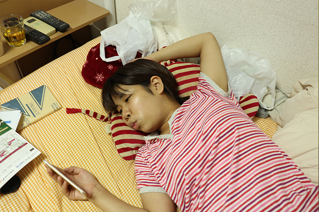 ベッドでスマホをいじるCHINTAI編集部の木村