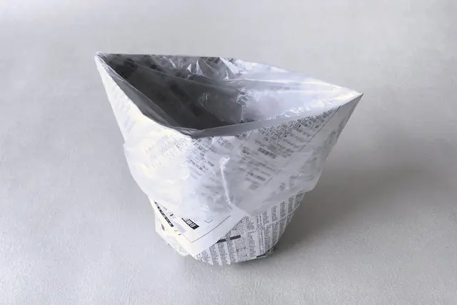 防災アイテム・新聞紙で作る食器の作り方の工程:上部を広げてポリ袋をかぶせた様子