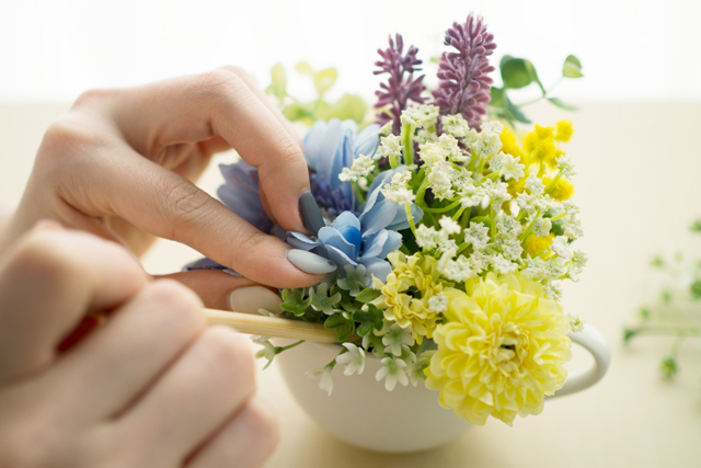 100均の材料で作る造花アレンジメントのレシピ：造花を入れた器の隙間に割り箸を使ってグリーンを詰めていく