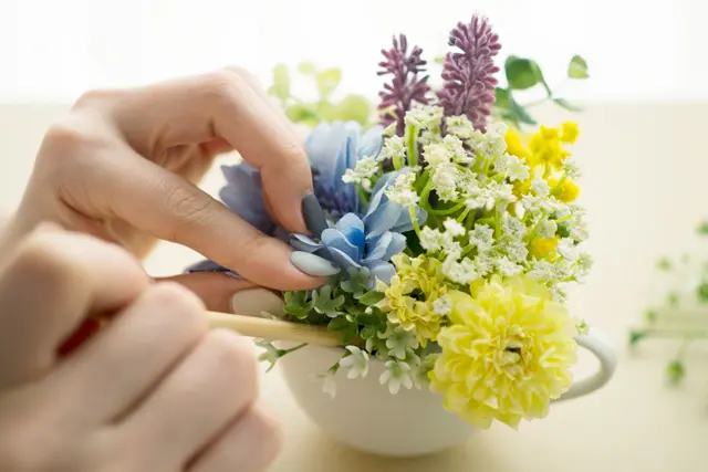 100均の材料で作る造花アレンジメントのレシピ:造花を入れた器の隙間に割り箸を使ってグリーンを詰めていく