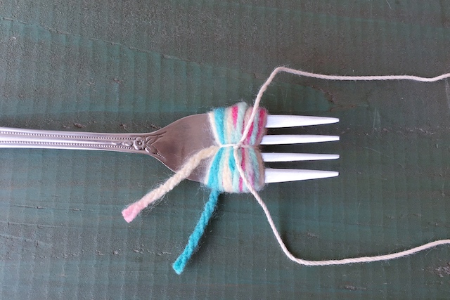 ポンポンの作り方：巻いた糸の真ん中をたこ糸で結ぶ