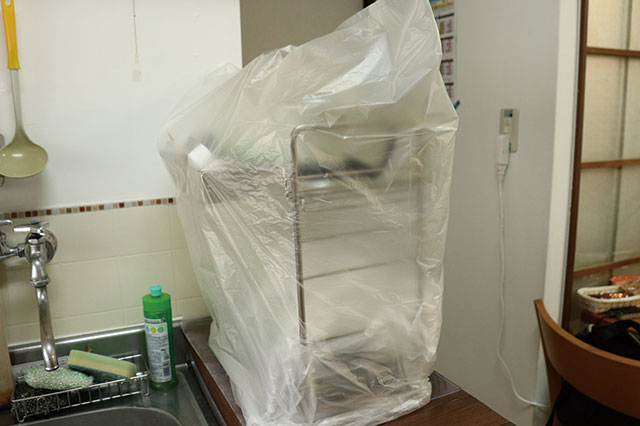 バルサンを焚くために、水切りかごを包む本多先生