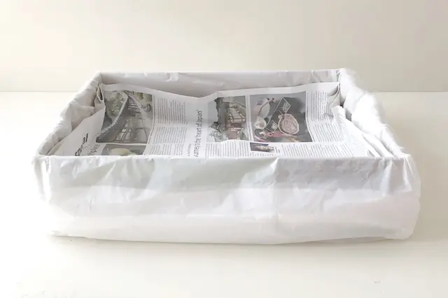 段ボール箱で作る猫用トイレのDIY工程:折った新聞紙をゴミ袋で覆った段ボールにセットする