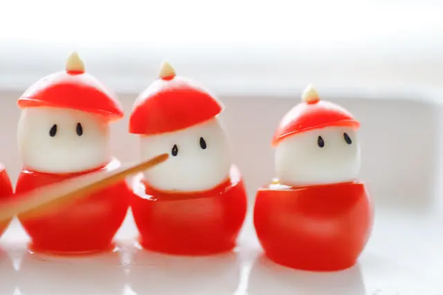 クリスマスパーティーを盛り上げる!カンタン・かわいい「フィンガーフード」のレシピ「プチトマトとうずらの卵のサンタクロース」の作り方:ごまで顔を付ける様子