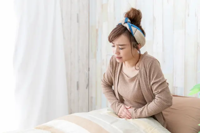 【ヨガインストラクターおすすめ】便秘解消効果が期待できる超簡単なヨガのポーズ2選 つらい スッキリ すぐ 即効性 体操 腹部を押さえて苦しむ女性