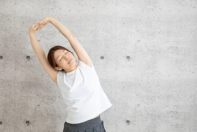 足のむくみの原因は?解消が期待できる生活習慣やマッサージを美容ライターが解説 伸びをする女性