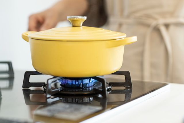 ガスコンロになべをかける女性
