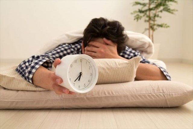 目覚まし時計をつかんでいる男性