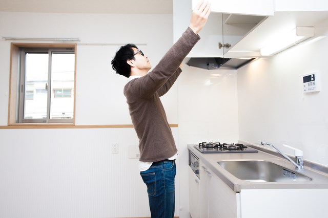 キッチン戸棚を開ける男性