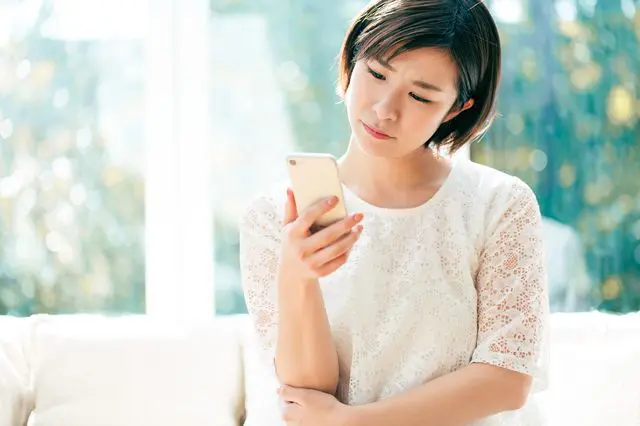 スマホを持ち悩む女性