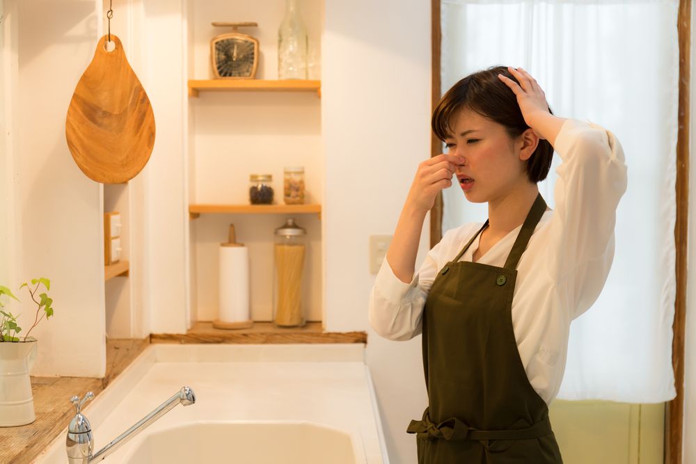 キッチンのにニオイに不快感を表す女性