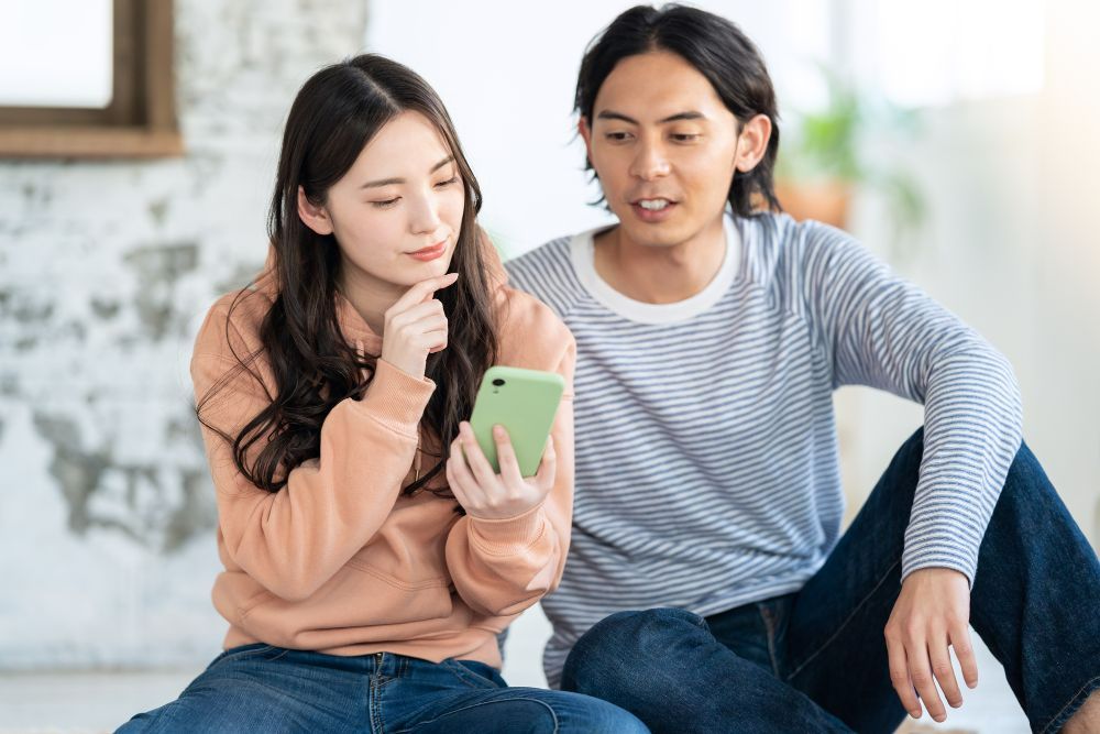 スマホを覗いて考えるカップル