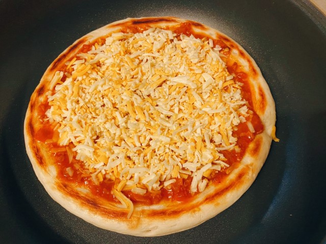 業務田スー子のかんたんアレンジレシピ_フライパンで作ろう簡単手作りピザ_ピザ生地表の面を焼き、ひっくり返してミートソースを塗りチーズをかける。