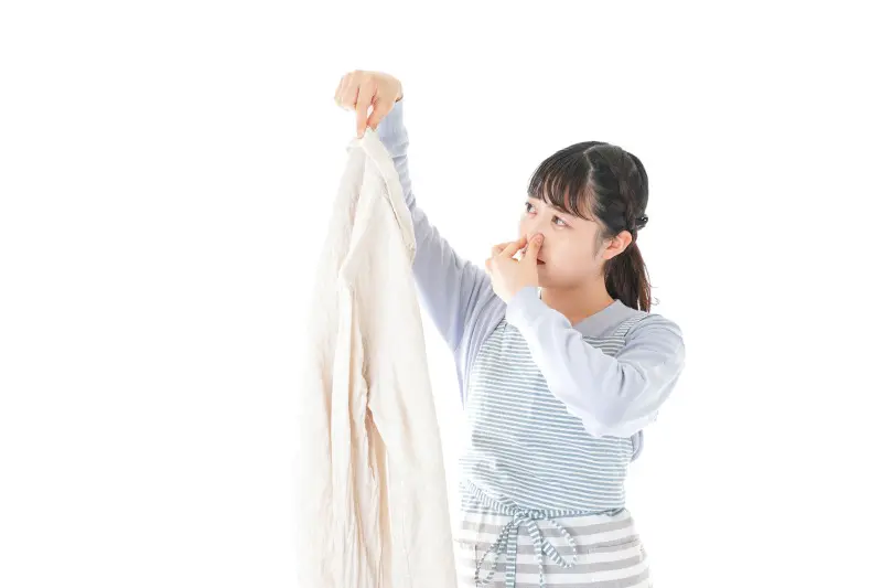 洗濯機の掃除_手に持った洗濯物のニオイを気にする女性