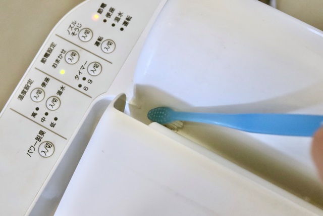歯ブラシを使って便器の隙間を掃除する様子