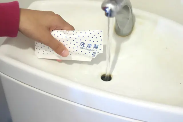 トイレタンクの漬けおき洗剤を入れている様子