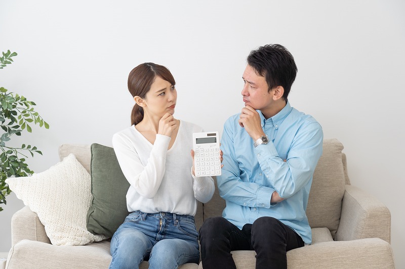 電卓を持ちながら悩む夫婦