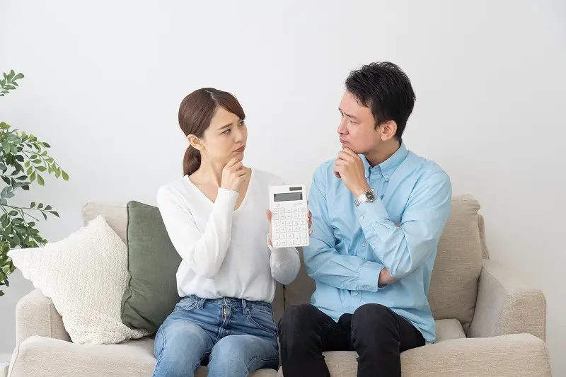 電卓を持ちながら悩む夫婦