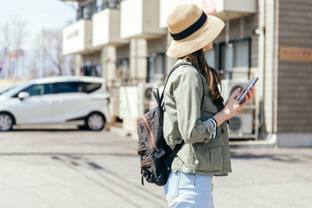 スマホを片手にマンションの外観を確認する女性